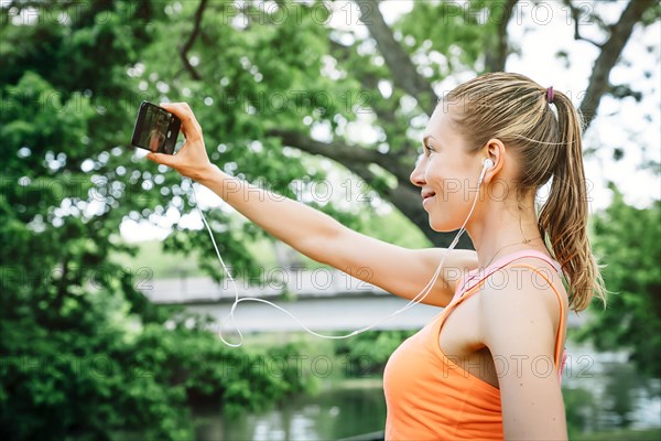 Caucasian woman using earbuds taking selfie
