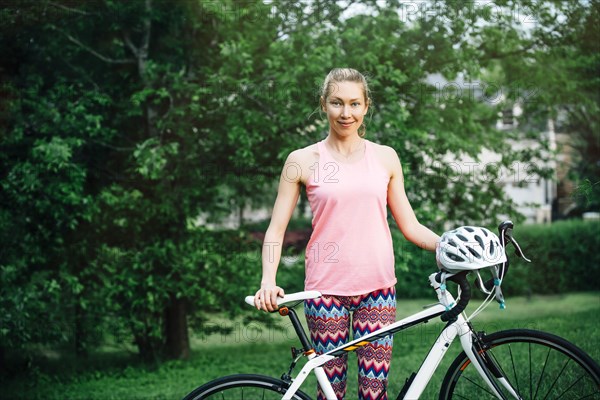 Smiling Caucasian woman posing holding bicycle