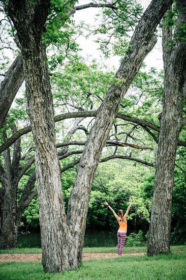 Caucasian woman standing with arms raised in park