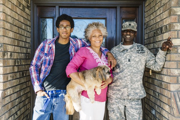 Black family posing with dog in doorway