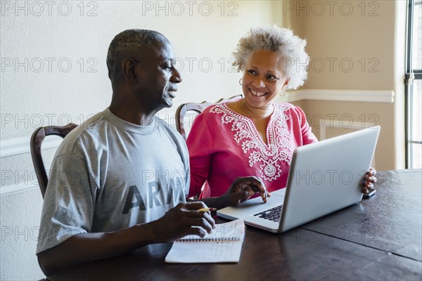 Black couple using laptop at table