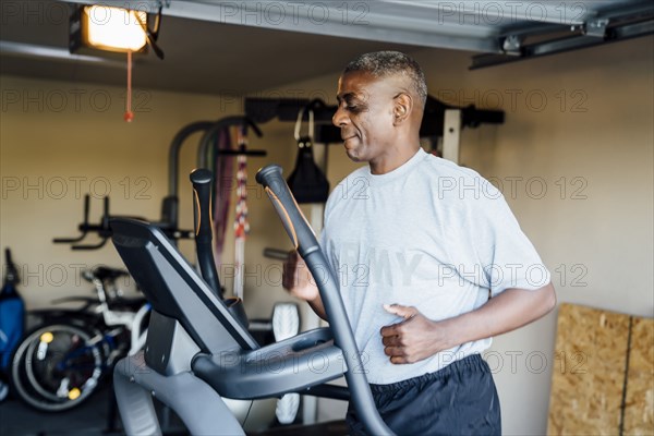 Black man running on treadmill in garage