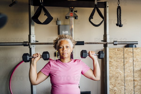 Black woman lifting weights in garage