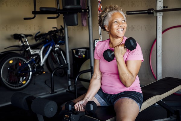 Black woman lifting weights in garage