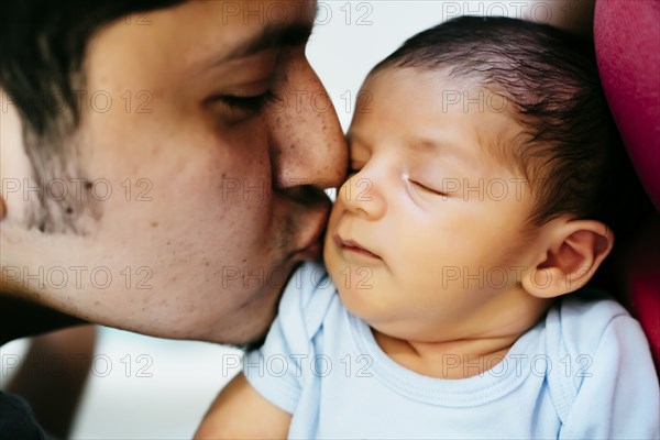 Hispanic man kissing baby boy on cheek