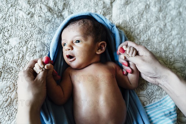 Hispanic woman holding hands of baby boy