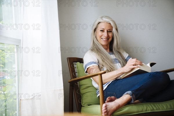 Caucasian woman sitting in armchair reading book