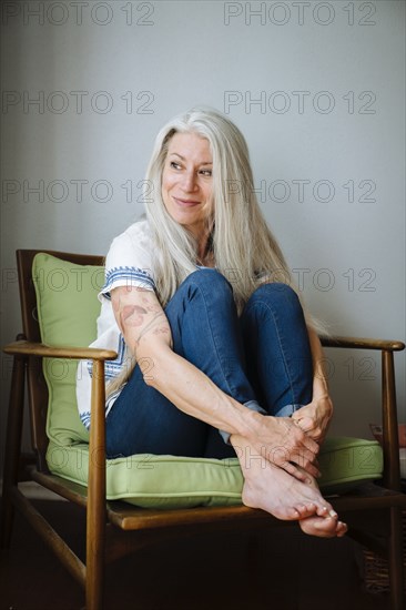 Caucasian woman sitting in armchair looking away