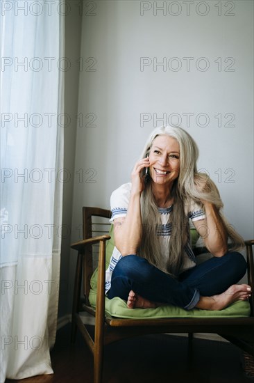 Caucasian woman sitting in armchair talking cell phone