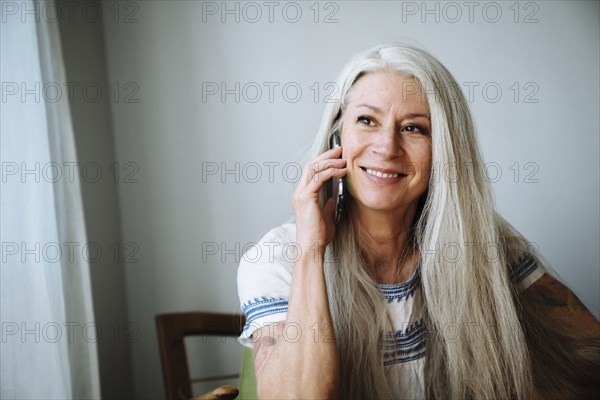 Caucasian woman sitting in armchair talking on cell phone