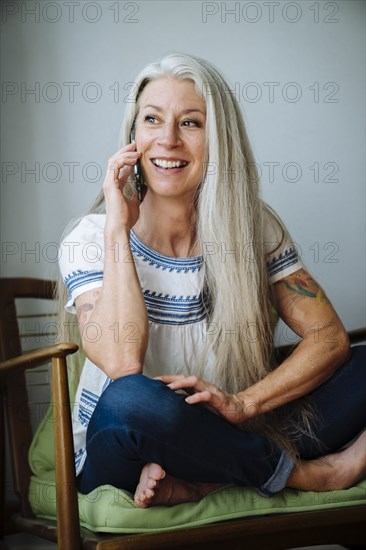 Caucasian woman sitting in armchair talking on cell phone