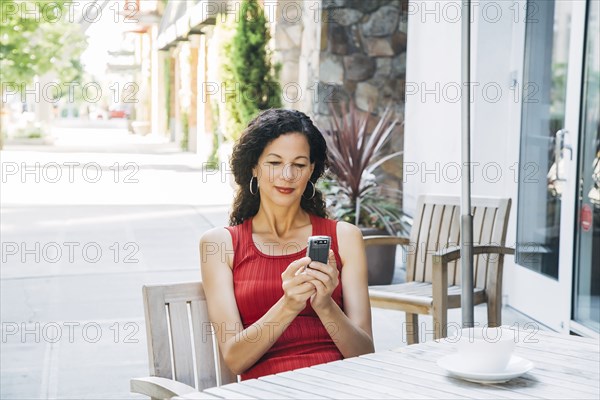 Mixed Race woman texting on cell phone at cafe