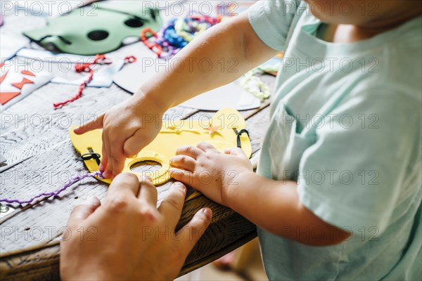 Caucasian boy making mask at table