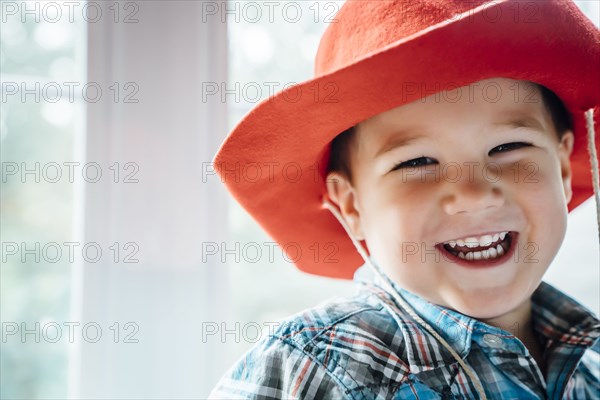 Laughing Caucasian boy wearing red cowboy hat