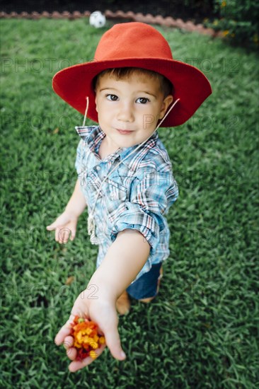 Caucasian boy wearing cowboy hat showing flowers in hand