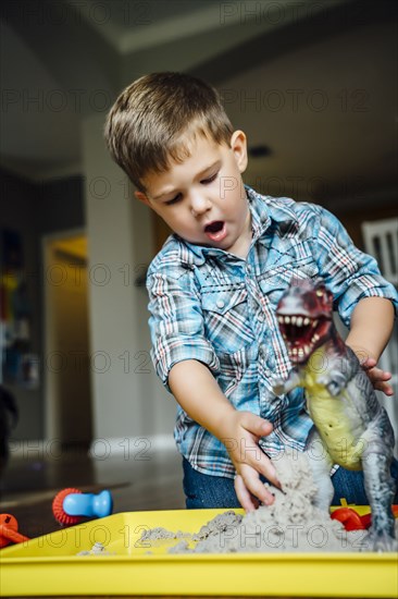 Caucasian boy playing with toy dinosaur