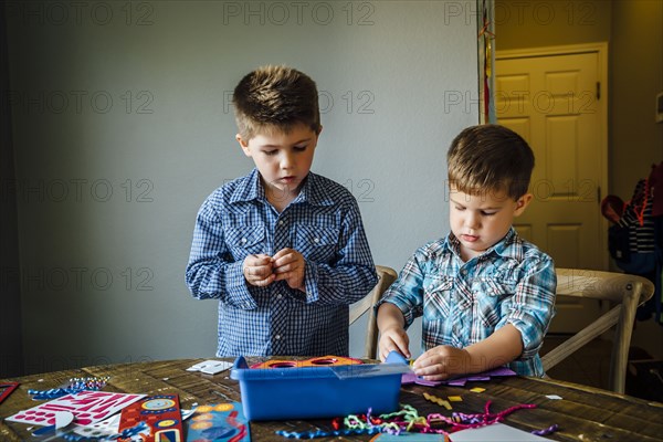 Caucasian boys making masks at table