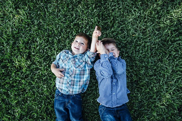 Caucasian boys laying in grass playing