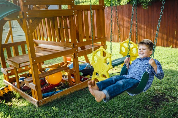 Smiling Caucasian boy n swing in backyard