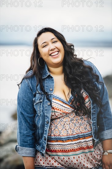 Smiling Mixed Race woman near ocean