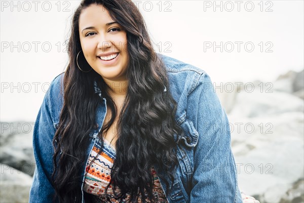 Smiling Mixed Race woman near ocean