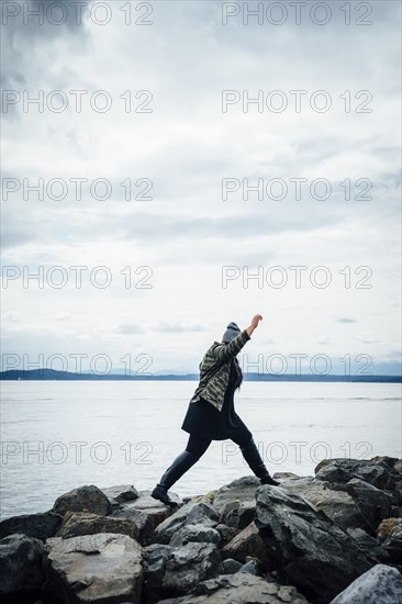 Mixed Race woman walking on rocks near ocean