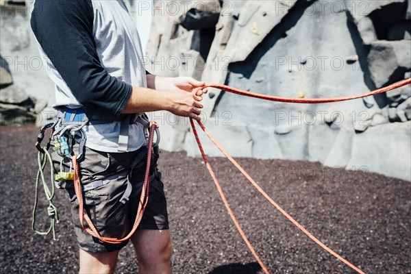 Caucasian man holding ropes at rock climbing wall