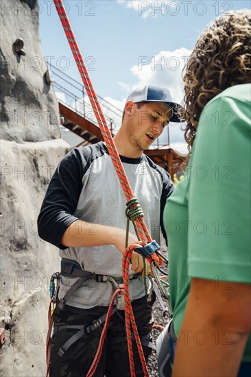 Caucasian man fastening rope to harness at rock climbing wall