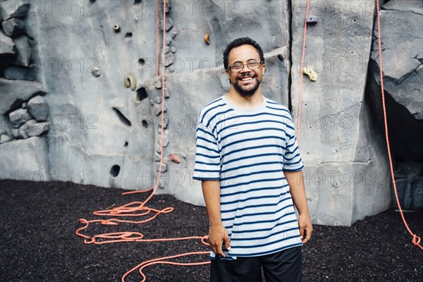 Mixed Race man smiling near rock climbing wall