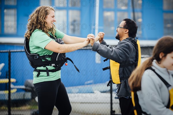 Man and woman wearing life-jackets holding hands