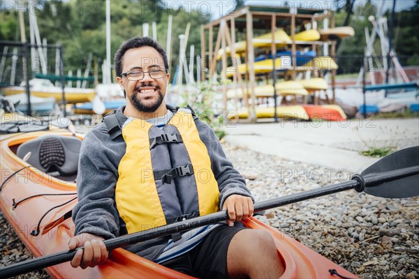 Mixed Rave man sitting in kayak holding paddle