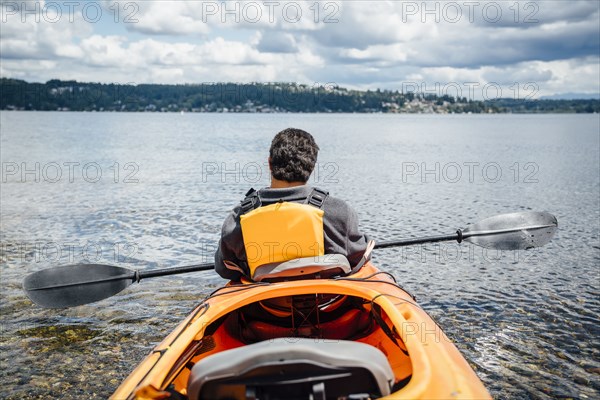 Mixed Rave man sitting in kayak holding paddle