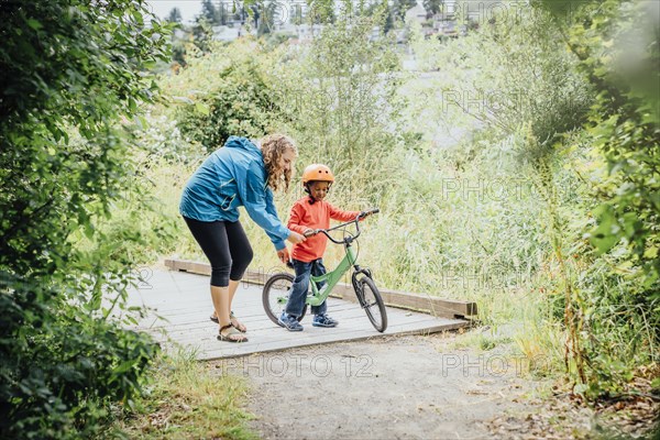 Mother helping son ride bicycle