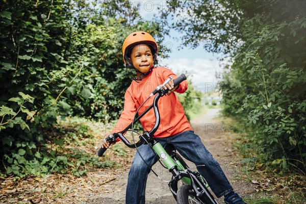 Black boy riding bicycle with helmet