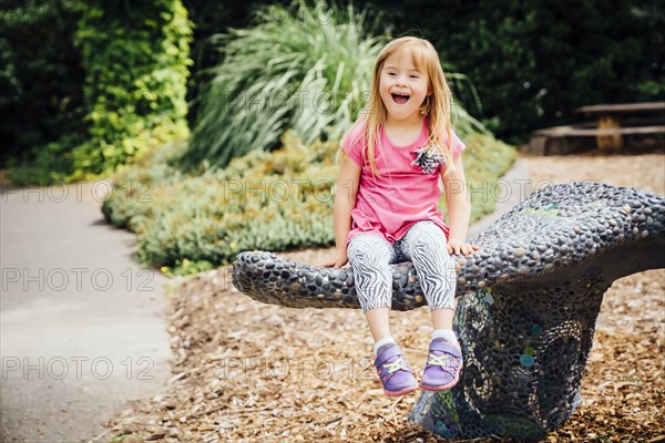 Smiling Mixed Race girl sitting on stone bench in park