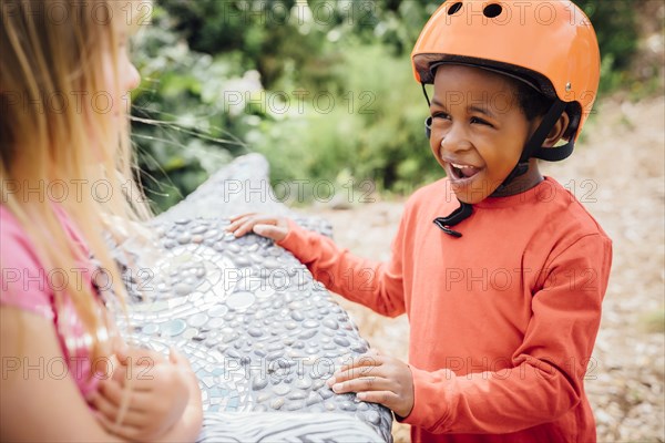 Smiling boy wearing helmet talking to girl on bench