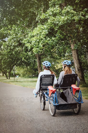 Caucasian mother and daughter riding tandem bicycle