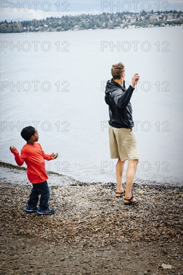 Father and son throwing rocks into river