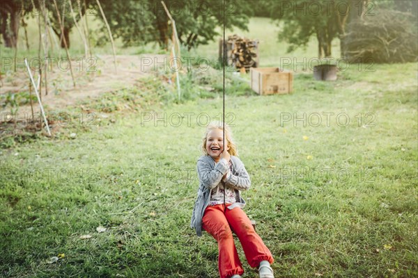 Smiling Caucasian girl on rope swing