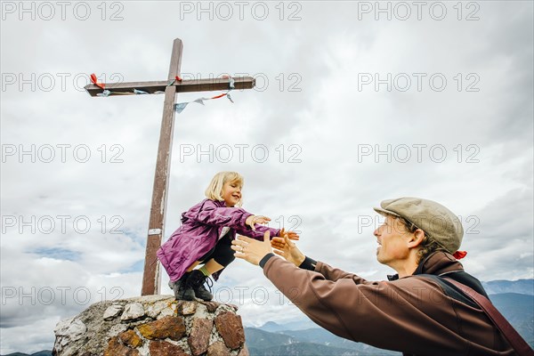 Caucasian father helping daughter on rock at crucifix