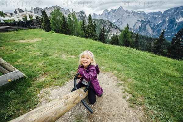 Caucasian girl on seesaw near mountain range