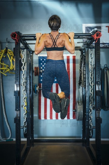 Caucasian woman doing chin-up in gymnasium