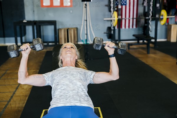 Caucasian woman lifting dumbbells in gymnasium