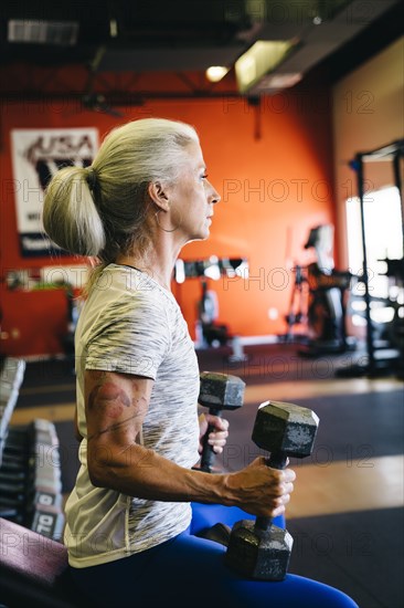 Caucasian woman lifting dumbbells in gymnasium