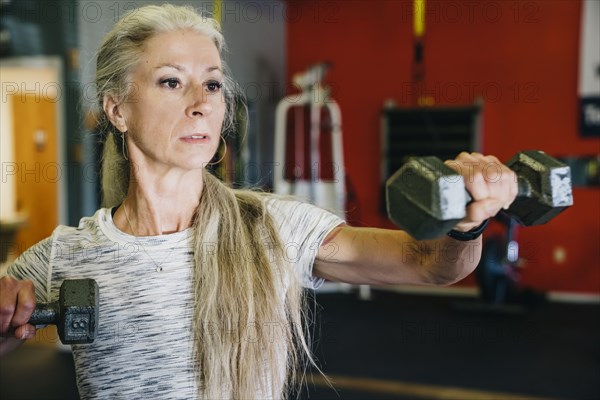 Caucasian woman lifting dumbbells in gymnasium