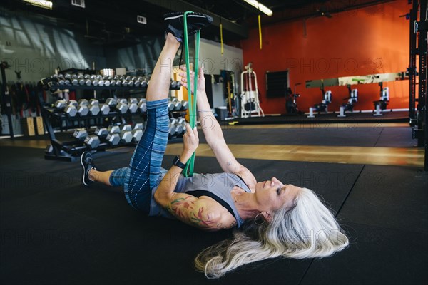 Caucasian woman stretching leg with resistance band