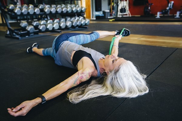 Caucasian woman stretching leg with resistance band