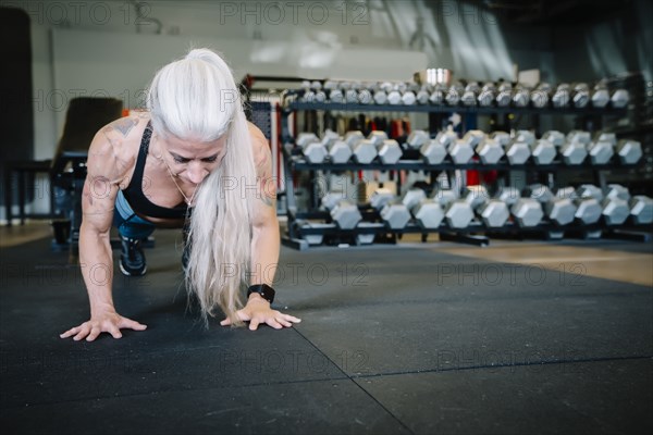 Caucasian woman doing push-up in gymnasium