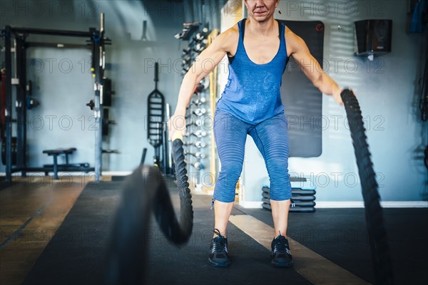 Caucasian woman using ropes in gymnasium