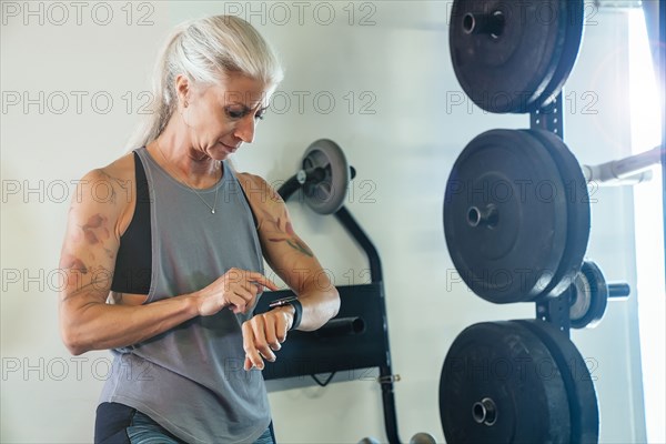 Caucasian woman tapping smart watch in gymnasium